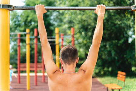 运动员将自己拉到单杠上在公园里做运动Teip背部和颈部图片