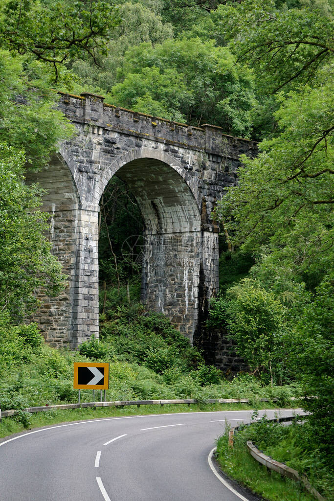 一座美丽的维多利亚时代石器拱门桥环绕着一片茂密的森林在苏格兰高原图片