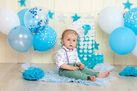 婴儿男孩用蛋糕和气球庆祝一年快乐的童图片