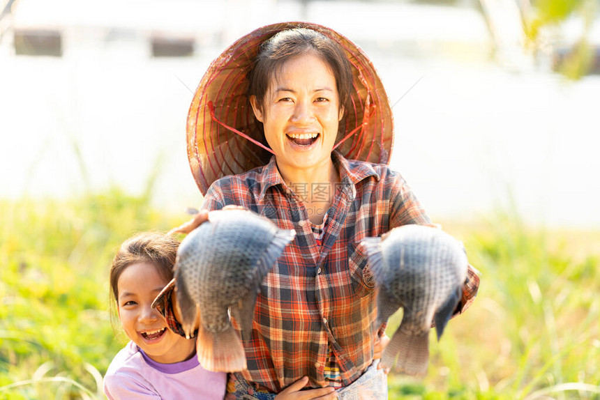 母女俩在湄公河上炫耀用漂浮的篮子养大的罗非鱼渔夫在商业农场喂鱼泰国东北部用来图片