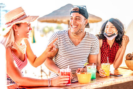 朋友三人组戴着口罩在海滩鸡尾酒吧喝酒图片