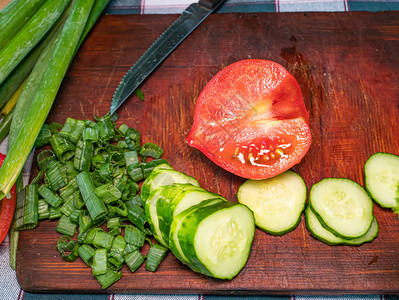 用刀在砧板上切一个红番茄绿色蔬菜沙拉厨师家庭厨房素食谱宣传照一个男人图片