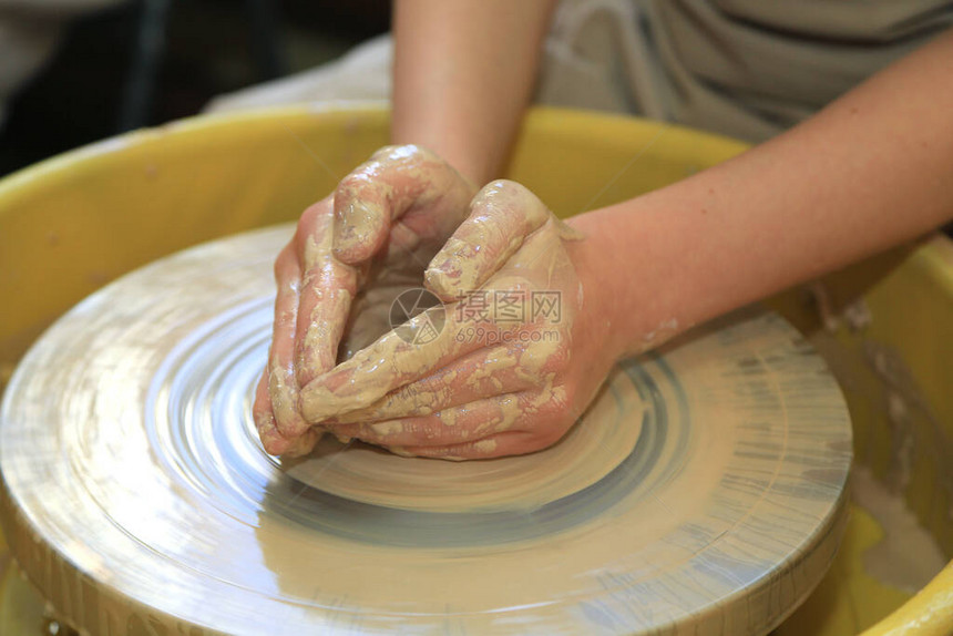 在陶器车间的陶器轮子上制造粘土制品图片