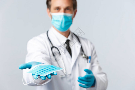 Covid19医护人员和疫苗接种概念穿PPE的医生递给你医用口罩图片