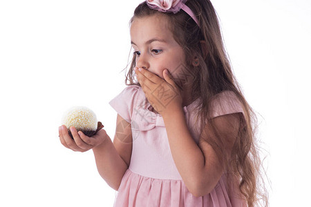 美丽的小女孩对一个美味的大巧克力椰子糖的球感到惊讶图片