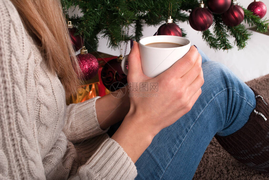 穿毛衣的女孩手拿咖啡腿上放着暖器和图片