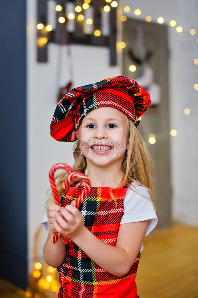 一个戴着厨师帽和围裙的孩子用棒糖庆祝圣诞节图片
