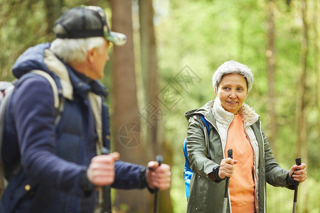 和丈夫一起在森林里散步时享受北欧步行的活跃老年妇女画像图片