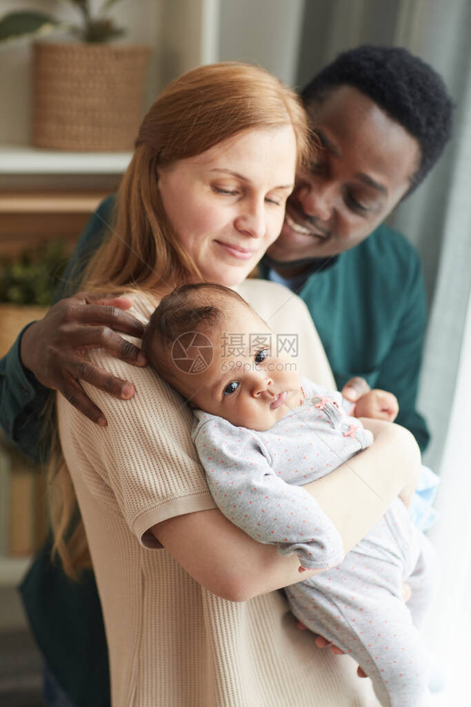 年轻的异族家庭抱着可爱的混血婴儿图片