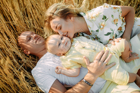 快乐的年轻家庭,孩子躺在黄色小麦田图片