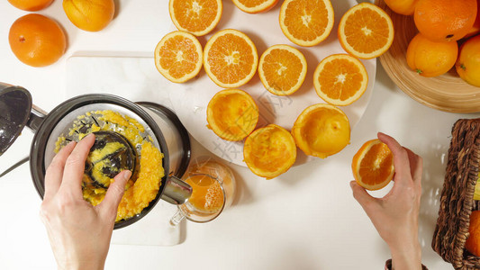 鲜榨橙汁白种女人用电动榨汁机挤橙子关闭在白色背景图片