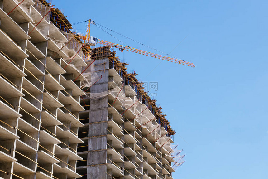 塔式起重机在建造公寓楼期间的建筑工地正在建设中的住宅楼的细节具有金属支柱和临时木栏杆图片
