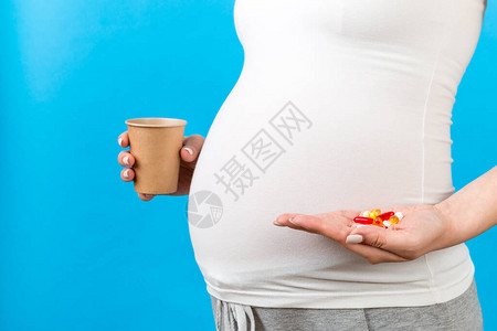 紧贴一个纸杯和一大批药片放在孕妇手中图片