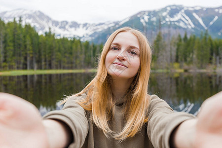 女孩旅游者在山湖自拍图片