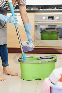 妇女戴橡胶手套在桶里为地板清洁用洗图片
