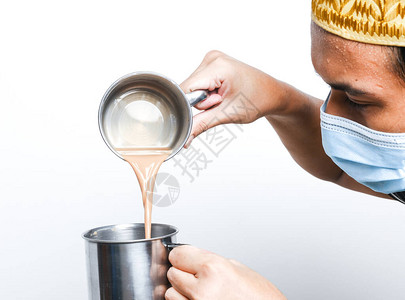 准备tehtarik并倒在杯子里的男人的照片甜奶茶被拉出来混合均匀背景图片