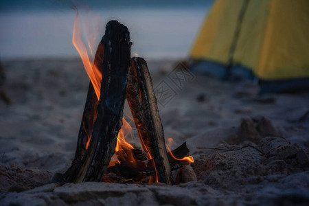 特写镜头火在海滩的篝火露营和帐篷旅行晚图片