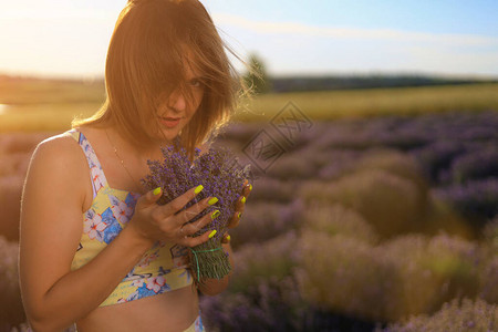 快乐的年轻美女在日落时走在紫衣草地上图片
