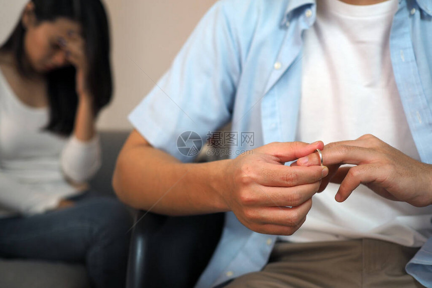 亚洲男人正在摘下结婚戒指背后有一位因家庭问题而压力重的妻子说再见图片