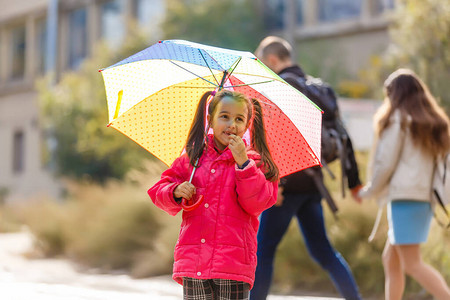 顽皮的小女孩躲在户外五颜六色的雨伞后面图片