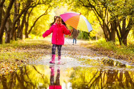 秋天下雨日时穿着多彩雨伞的可爱小孩女图片