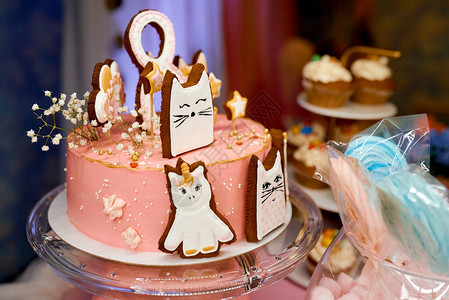 装饰着小猫生日照片的摊位上粉红色和红蛋糕图片