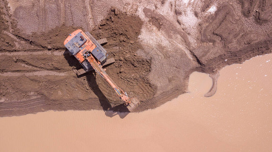 挖掘机正在一个新的建筑工地的湿土中运图片