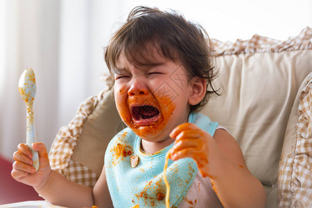 可爱的蹒跚学步的小女孩或婴儿在婴儿椅上吃完食物后不满意会哭图片
