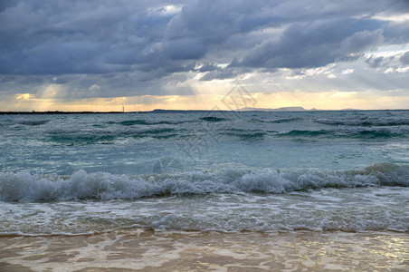 海面上风雨如磐的乌云沙滩和卷曲的海浪图片