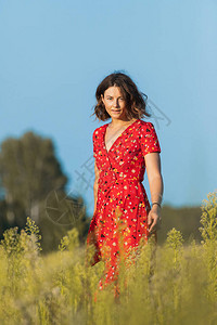一个卷发女孩在田野上穿着红色长裙浪漫地走过女自由解放和图片