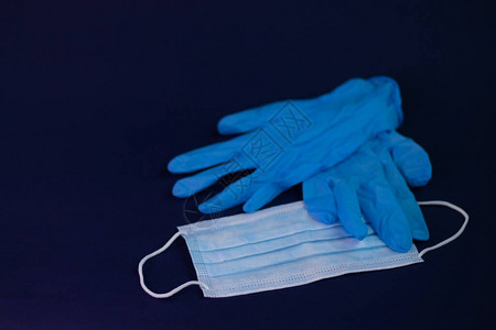 深蓝背景的蓝色医疗手套和面罩Corona概念期间的医学和健图片