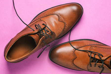 棕色男鞋特写粉红色背景上解开鞋带的经典鞋婚礼鞋日常步行鞋和办公室图片