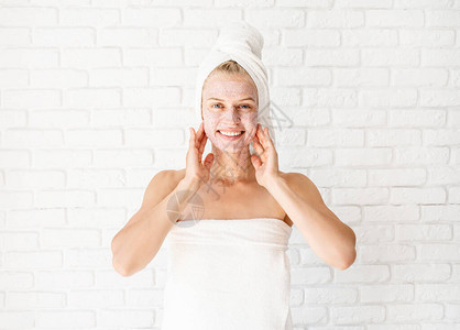 有吸引力的微笑女人在她的皮肤上应用磨砂膏面部清洁概念水疗和美容图片