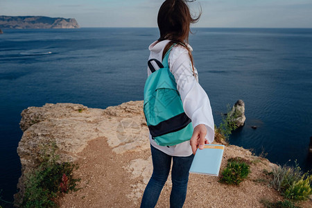 一位带着背包和护照的美丽的年轻女子在海边享受节日图片