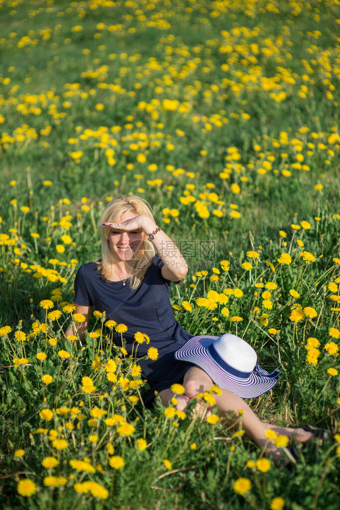 一个美丽的年轻金发美女在阳光明媚的夏日在一个盛开的黄花图片