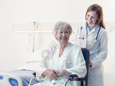 在医院或养老院的轮椅上微笑快乐的老年妇女在受伤或手术康复期间被医图片