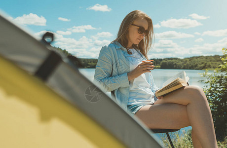 在湖边露营帐篷附近看书的女人图片