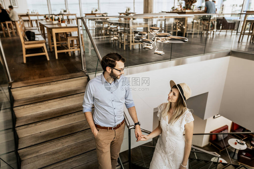 一对时髦的夫妇在休息室楼梯上互相看对方幸福的家庭从楼梯图片