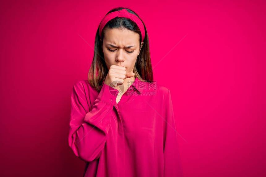 身着散装衬衫站立在孤立的粉红色背景上感到不适和咳嗽作为冷血或支气管炎症状的年轻美图片