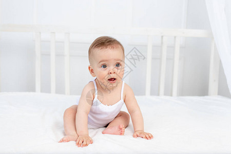 个月大的微笑女婴穿着白色衣服坐在儿童房的婴儿床里图片