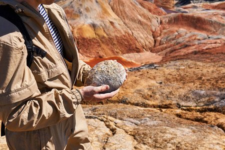 古生物学家持有恐龙化石蛋在沙漠地貌背景中图片