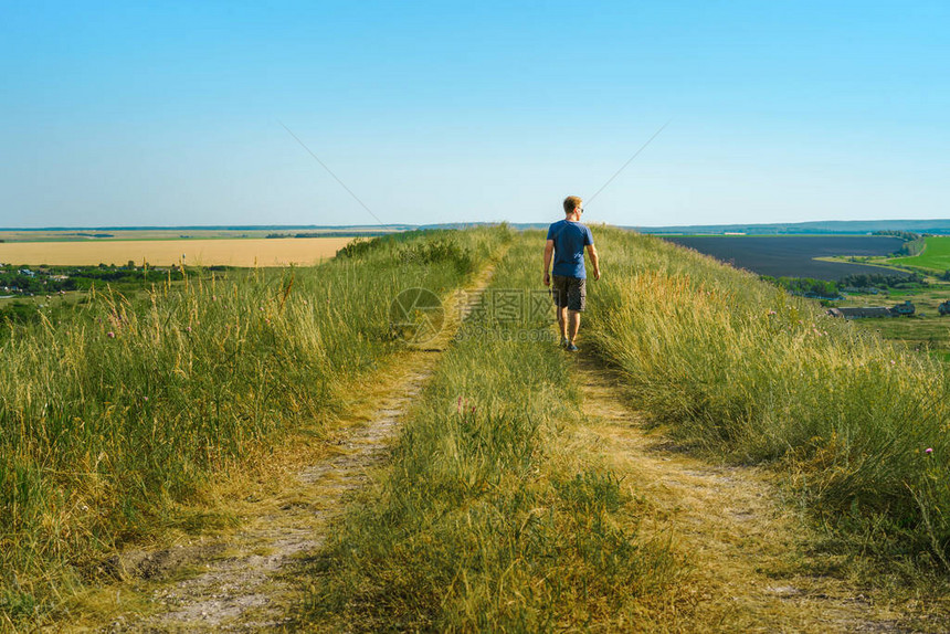 一名年轻男旅游者在山上俯视田野图片