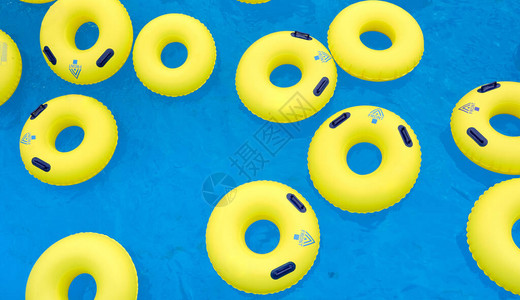 游泳池蓝色水面上几个黄色游泳充气救生圈图片