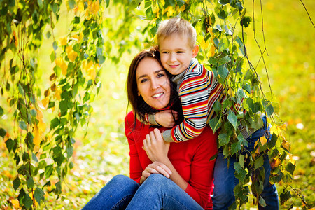 快乐的家庭母亲和儿子男孩在自然的秋天拥抱着甜蜜的情感看图片