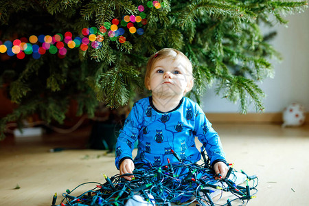 洒扫庭除可爱的女婴从圣诞树上摘下节日装饰品儿童拿着轻园庆祝之后的家庭除背景