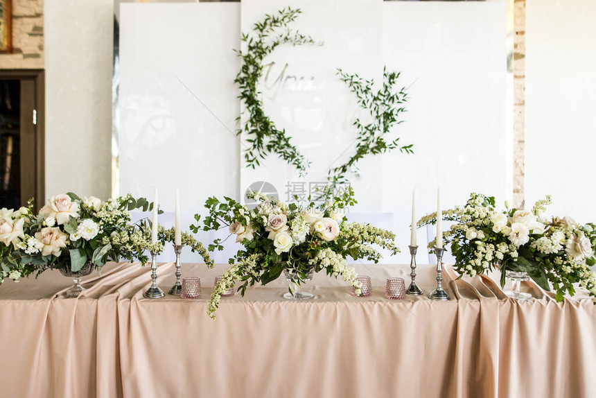 新婚夫妇主席团在婚礼上的特写新娘和新郎在餐厅用鲜花和蜡烛的桌子新婚夫妇的宴会桌图片