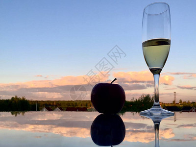 一杯酒和一个苹果的深色剪影在玻璃桌子的镜面上图片