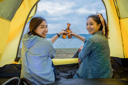 亚裔女朋友与朋友一同在日落时在湖边露营图片