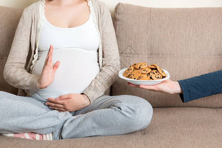 坐在沙发上的孕妇的特写拒绝吃饼干图片
