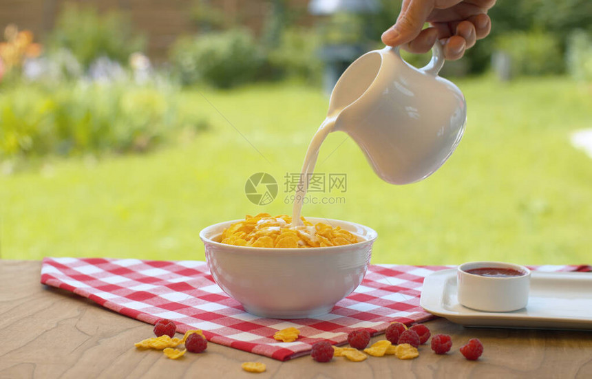 近身的雄手用玉米片把牛奶倒进碗里无法辨认的男子在花园做早餐健康图片